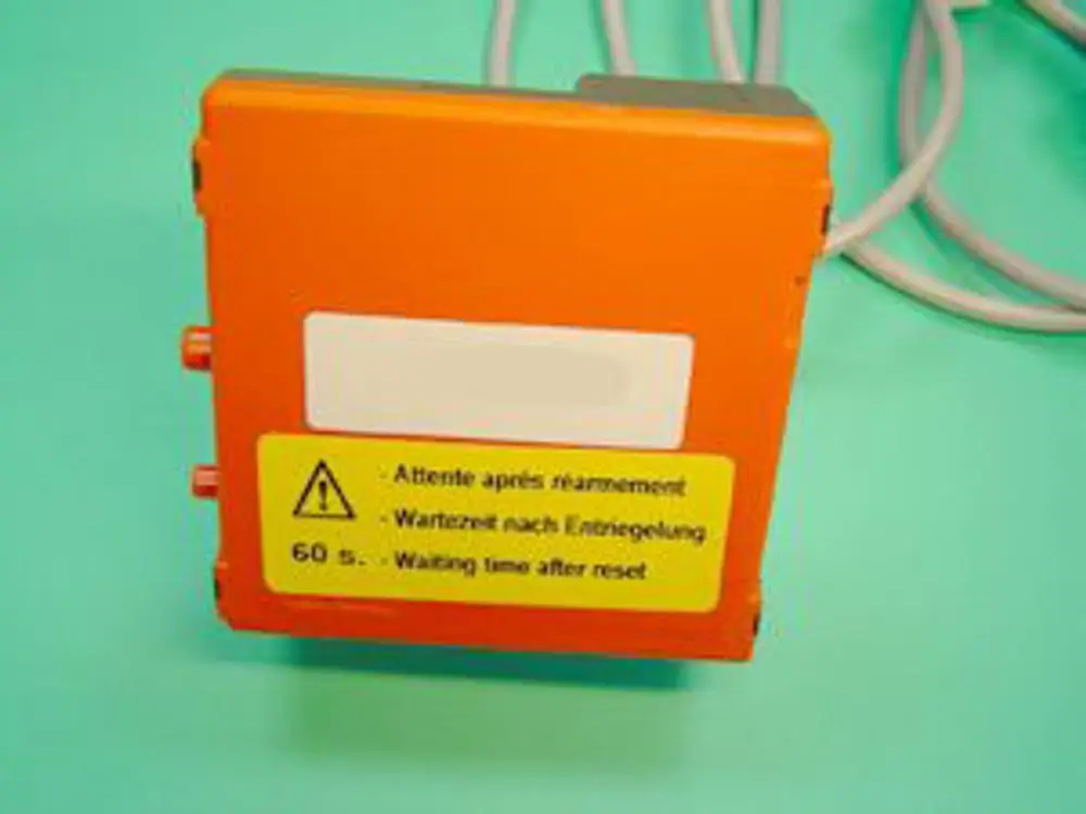 Remeha Gasfeuerungsautomat in Orange mit Anschlussmöglichkeiten. Beschriftung in mehreren Sprachen, einschließlich Warnhinweis und Anweisungen zur Wartezeit nach dem Zurücksetzen.